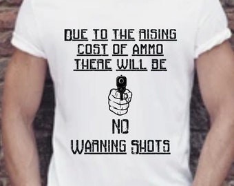 Puede incluir: Camiseta blanca con un gráfico negro que dice "Due to the rising cost of ammo there will be no warning shots". El gráfico también incluye una silueta negra de una mano sosteniendo un arma.