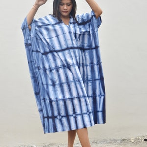May include: A long, flowing blue and white tie-dye dress with a V-neckline. The dress is loose-fitting and has a relaxed silhouette.