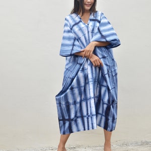 May include: A blue and white tie-dye maxi dress with a V-neck and 3/4 sleeves. The dress is loose-fitting and has a flowing silhouette.