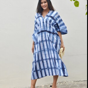 May include: A blue and white tie-dye maxi dress with a v-neck and short sleeves. The dress is loose fitting and has a flowing silhouette.