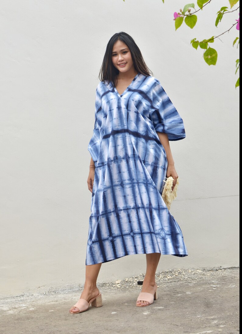May include: A blue and white tie-dye maxi dress with a v-neck and short sleeves. The dress is loose fitting and has a flowing silhouette.