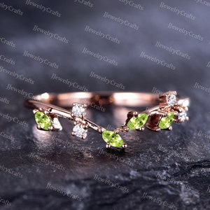 May include: A delicate gold ring with a vine design featuring small green peridot gemstones and sparkling diamonds.