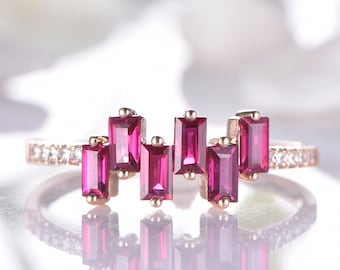 May include: A rose gold ring with a row of small diamonds and a cascading design of seven rectangular ruby gemstones.
