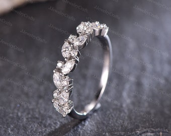 May include: A silver band ring with a delicate design of marquise and round cut diamonds set in a pave setting.