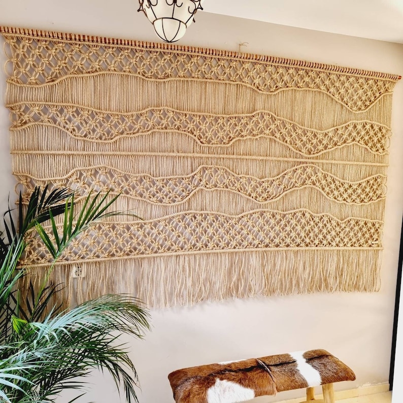 Jute wandkleed macramé met golvende lijnen. Zandkleurig modern wandkleed met zwevende lijnen
