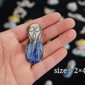 Könnte beinhalten: Eine handbemalte Keramikfigur von Der Schrei, einem berühmten Gemälde von Edvard Munch. Die Figur ist in Blau und Weiß bemalt und hat einen überraschten Ausdruck. Die Figur ist 2 mal 4,5 Zentimeter groß.