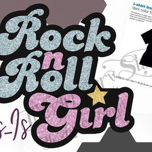 May include: A graphic design featuring the text Rock n Roll Girl in glittery light blue and pink letters with a gold star. The image includes a package of t-shirt transfers for dark color fabrics, showing a black t-shirt with a circular graphic.