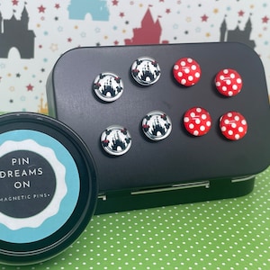 May include: A set of eight magnetic pins in a black tin. The pins feature images of a castle and red polka dots. The tin has a label that reads "Pin Dreams On - Magnetic Pins."