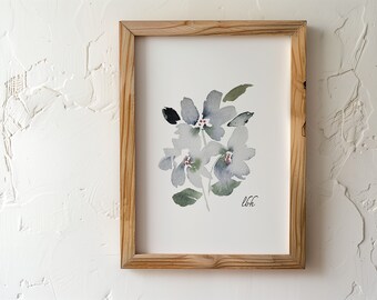 May include: Watercolor floral art print in a natural wood frame. The artwork features soft, gray-blue flowers with green leaves and red accents. The artist's initials, "lbh", are in the lower right corner. The frame is made of light-colored wood.