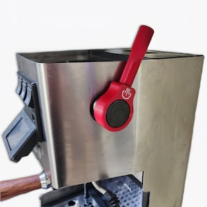 Könnte beinhalten: Eine Espressomaschine aus Edelstahl mit einem roten Hebel. Die Maschine hat ein digitales Display und eine Tropfschale.