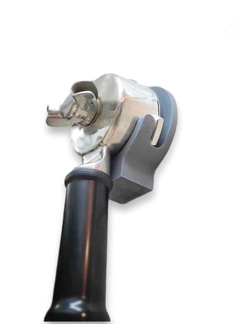 May include: A chrome-colored, mechanical device with a black handle and a gray support structure. The device has a complex design with multiple components and a shiny, reflective surface. The handle is cylindrical and tapers towards the base.