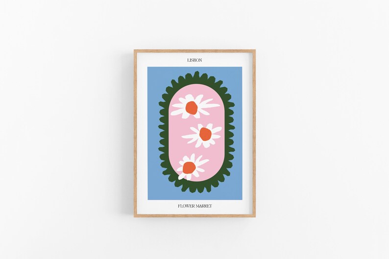 May include: A framed print with a blue background and a pink oval with three white flowers with orange centers. The oval is surrounded by a green border. The text "LISBON" and "FLOWER MARKET" are printed below the image.
