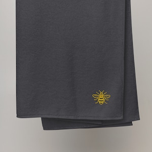 May include: A dark gray fleece throw blanket with a gold embroidered bee design.