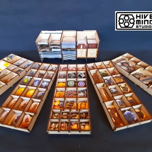 May include: Wooden organiser for the board game "7 Wonders Duel". The organiser includes multiple trays for storing the game's components, including cards, tokens, and tiles. The organiser is made of natural wood and has a light brown finish. The organiser is designed to fit inside the game's box.