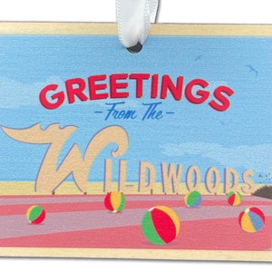 May include: A wooden postcard with a blue sky and beach scene. It says "Greetings - From The - Wildwoods" with a large white "W" and beach balls.