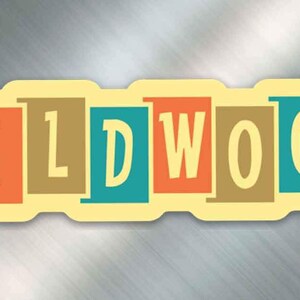 May include: A yellow and white sticker with the word "WILDWOOD" in colorful block letters. The letters are in shades of teal, orange, brown, and yellow.
