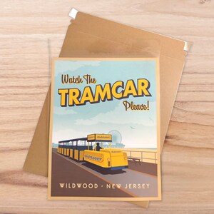 Op de afbeelding: Een ansichtkaart in vintage stijl met een gele tram en de tekst "Watch the Tramcar Please!" en "Wildwood, New Jersey".