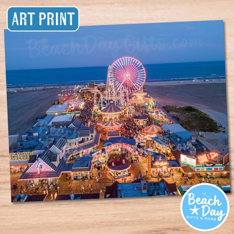 May include: Art print featuring a vibrant aerial view of a boardwalk at dusk. A large, illuminated Ferris wheel dominates the scene, surrounded by amusement park rides and buildings. The text "Beach Day Gifts.com" and "Beach Day Gifts & More" are visible.