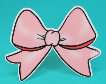 May include: A die-cut sticker featuring a light pink bow with a central knot and two hanging tails. The illustration has a thick black outline and a thin red accent line along the bottom edge of the bow loops, creating a bold graphic appearance.