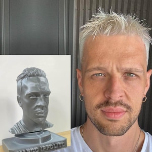 Peut inclure: Un buste en 3D imprimé d'une personne aux cheveux courts. Le buste est gris et repose sur une base grise avec le nom "Marco Ippolito" imprimé dessus. Le buste est à côté d'une personne aux cheveux courts et blancs.