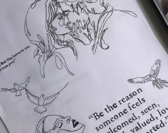 May include: A black and white line drawing of two people embracing. The drawing is on a white piece of paper. The text "Be the reason someone feels welcomed, seen, heard, valued, loved and supported." is written below the drawing.