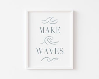 以下が含まれることがあります： 「MAKE WAVES」の文字が薄い青色のフォントで書かれたフレーム付きプリント。波のイラストが添えられています。白いフレームがプリントを囲み、背景も白です。