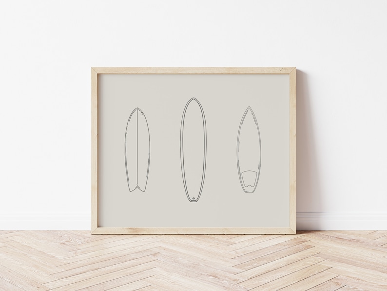 May include: A framed print with a minimalist line drawing of three surfboards on a beige background.