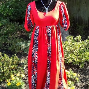 May include: A red maxi dress with a white and blue floral print. The dress has a scoop neckline, puff sleeves, and a gathered waist.