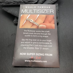 May include: A gray card with the text "WORLD FAMOUS MULTISIZER" and instructions on how to use the ring sizer. The card shows a ring sizer being used on a finger. The text includes "NOW SUPER SIZING FROM A-Z+9".