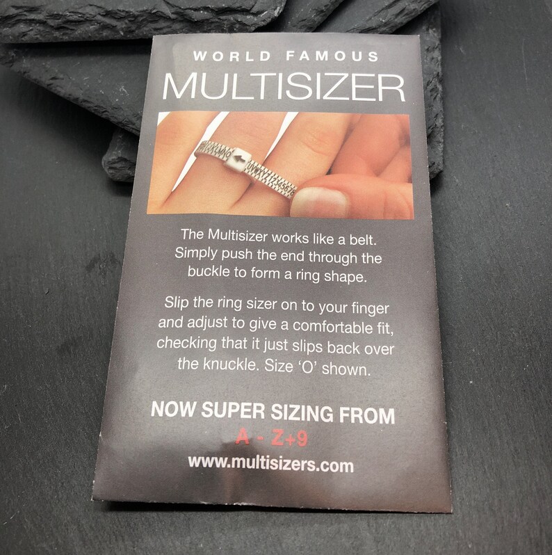 May include: A gray card with the text "WORLD FAMOUS MULTISIZER" and instructions on how to use the ring sizer. The card shows a ring sizer being used on a finger. The text includes "NOW SUPER SIZING FROM A-Z+9".