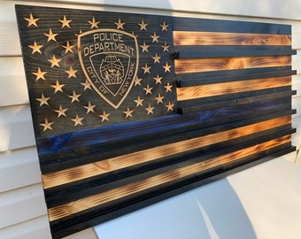 May include: A wooden American flag with a blue line, a black and brown wood grain finish, and a black metal police shield with the text "Police Department City of New York".