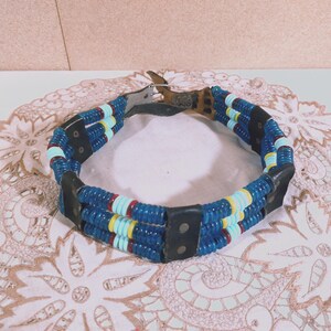 May include: A beaded belt with blue, white, and red beads. The belt is made of leather and has a buckle.