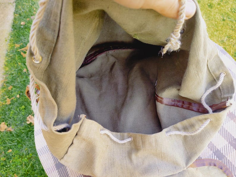 Op de afbeelding: Een beige canvas trekkoordtas met een bruine leren bies en een wit touw trekkoord. De tas is open en de binnenkant is zichtbaar.