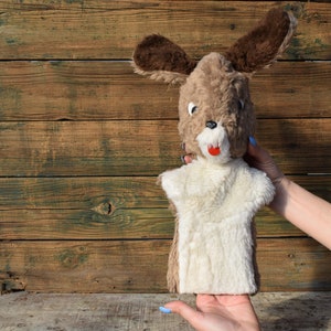 Könnte beinhalten: Eine braune und weiße Puppe mit langen Ohren und einer roten Nase. Die Puppe wird von einer Hand mit blauem Nagellack gehalten.