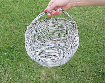 May include: A white wicker basket with a handle. The basket is woven with a tight, intricate pattern.