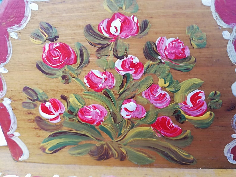 May include: Hand-painted wooden box with a floral design. The box features a bouquet of pink and white roses with green leaves on a light brown background.