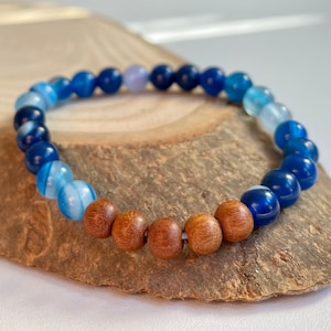 Könnte beinhalten: Ein blaues und braunes Perlenarmband mit einem Farbverlauf aus blauen Achatperlen und braunen Holzperlen.