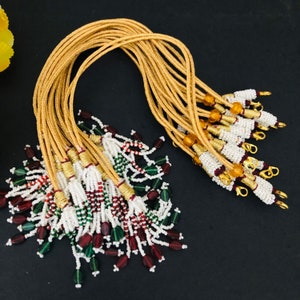 May include: A bundle of gold cord necklaces with white, green, and red beads and gold clasps.