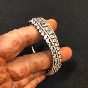 Puede incluir: Un conjunto de tres pulseras de plata, cada una con una fila de piedras transparentes en forma de marquesa.