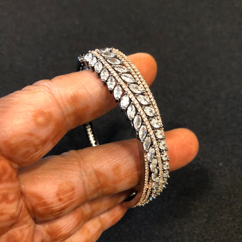 Puede incluir: Un conjunto de tres pulseras de plata, cada una con una fila de piedras transparentes en forma de marquesa.