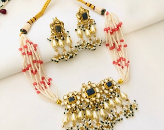 May include: A gold necklace with a blue stone pendant and pearl drops. The necklace is made of white and pink beads and has a matching pair of earrings.