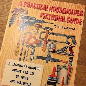 May include: A vintage book cover with a yellow background and a title that reads "A Practical Householder Pictorial Guide by F.J. Camm". The cover features an illustration of various tools, including a drill, saw, hammer, and paintbrush.