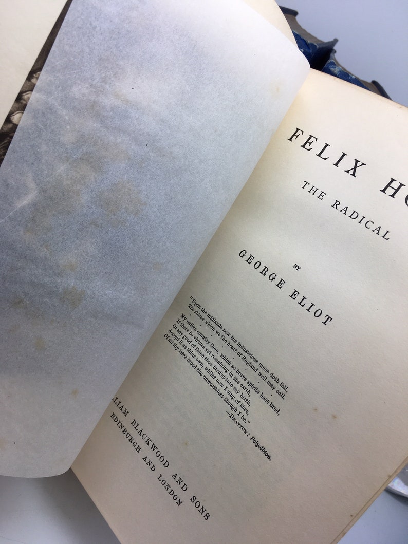 May include: A vintage book cover with the title "Felix Holt, The Radical" by George Eliot. The cover is cream-colored with black text and a quote from the book.