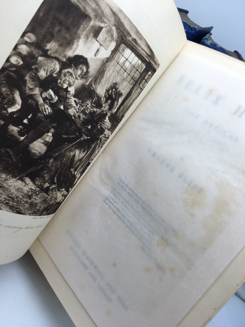 May include: A black and white illustration of a group of people gathered around a table in a dimly lit room. The illustration is from a vintage book.