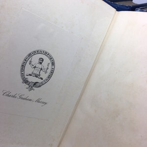 May include: A close-up of a book's inside cover with a black and white illustration of a man holding a sword and a shield. The illustration is surrounded by a circle with the text "Furth Fortune and Fill the Fetters". The text "Charles Graham Murray" is written in cursive below the illustration.