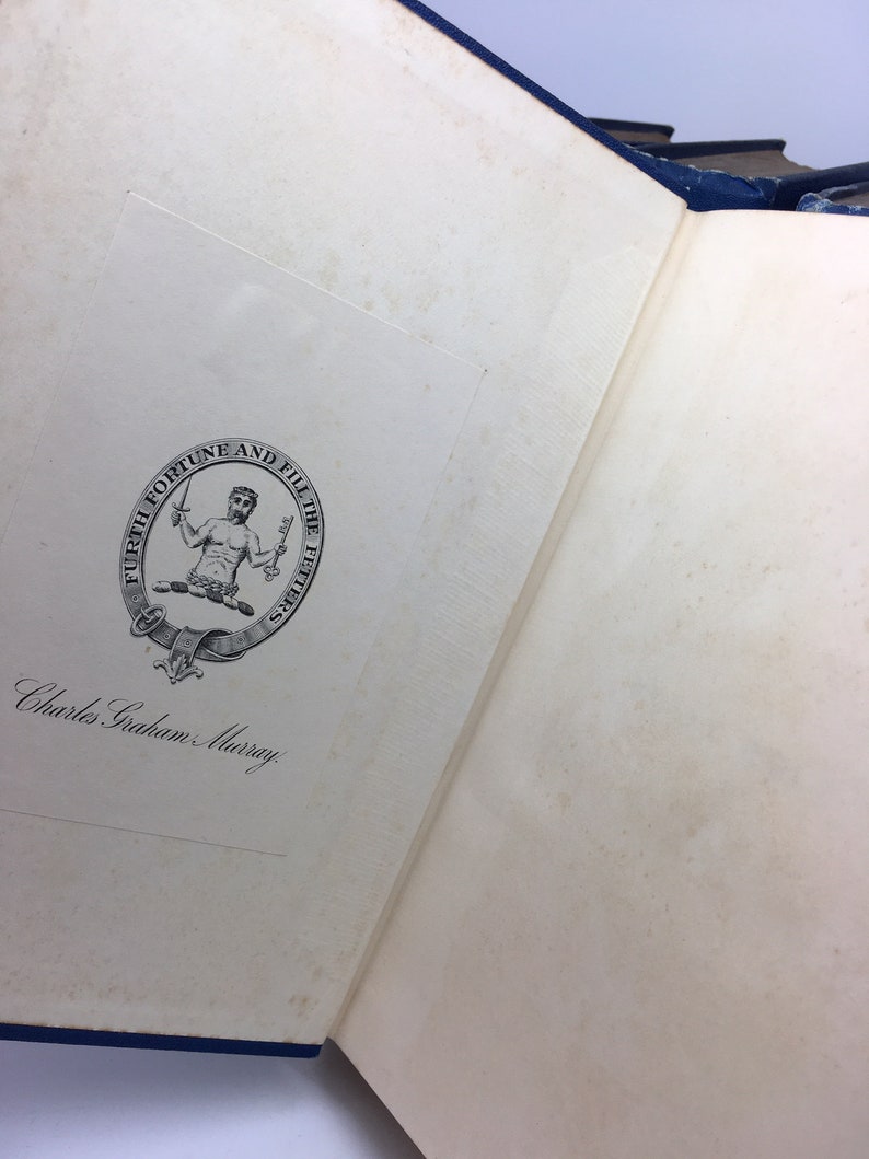 May include: A close-up of a book's inside cover with a black and white illustration of a man holding a sword and a shield. The illustration is surrounded by a circle with the text "Furth Fortune and Fill the Fetters". The text "Charles Graham Murray" is written in cursive below the illustration.