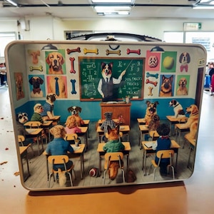 May include: A vintage metal lunchbox with a colorful illustration of dogs in a classroom setting. The teacher dog is at the front of the class, wearing a suit and tie, and holding a pointer. The students are sitting at desks, wearing clothes and hats. The chalkboard behind the teacher says "Dog Tricks".