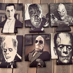 May include: A set of six black and white foam can coolers featuring detailed illustrations of classic horror movie characters including Dracula, the Wolf Man, the Creature from the Black Lagoon, the Phantom of the Opera, the Invisible Man, and Frankenstein's monster.