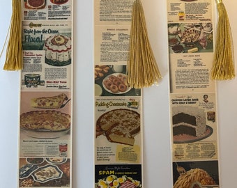 May include: Three vintage bookmark recipe cards with images of food and text. The first card features a meatloaf recipe with the text "Me-too Meat Loaf?" The second card features a pudding cheesecake recipe with the text "Pudding Cheesecake". The third card features a chiffon layer cake recipe with the text "Chiffon Layer Cake with Only 2 Eggs!"