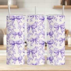 May include: Three stainless steel tumblers with a white background and a purple bow pattern.